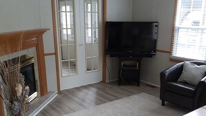 A living room with a fireplace, a flat-screen TV, a sofa, and a dining table. - The Big Happy Place (Fergus)