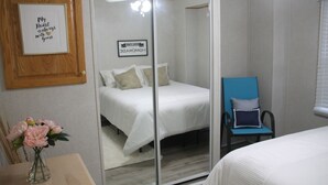 A bedroom with a bed, a chair, a mirror, and a framed quote on the wall. - The Big Happy Place (Fergus)