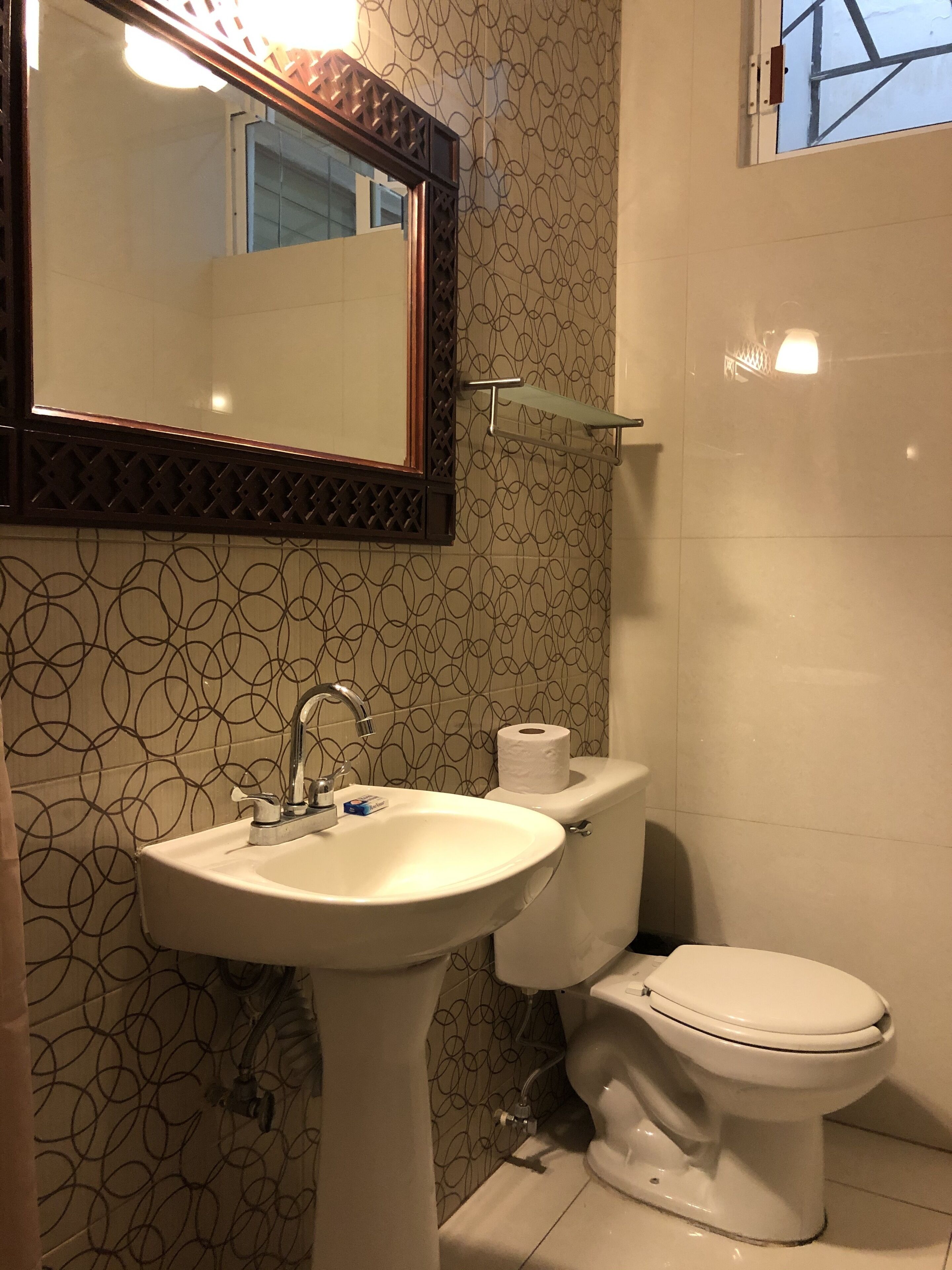 Un baño con un lavabo blanco, un inodoro y un espejo con un marco decorativo.