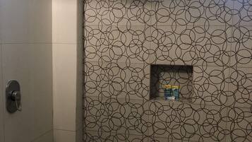 A bathroom with a shower, a window, and a patterned wall.