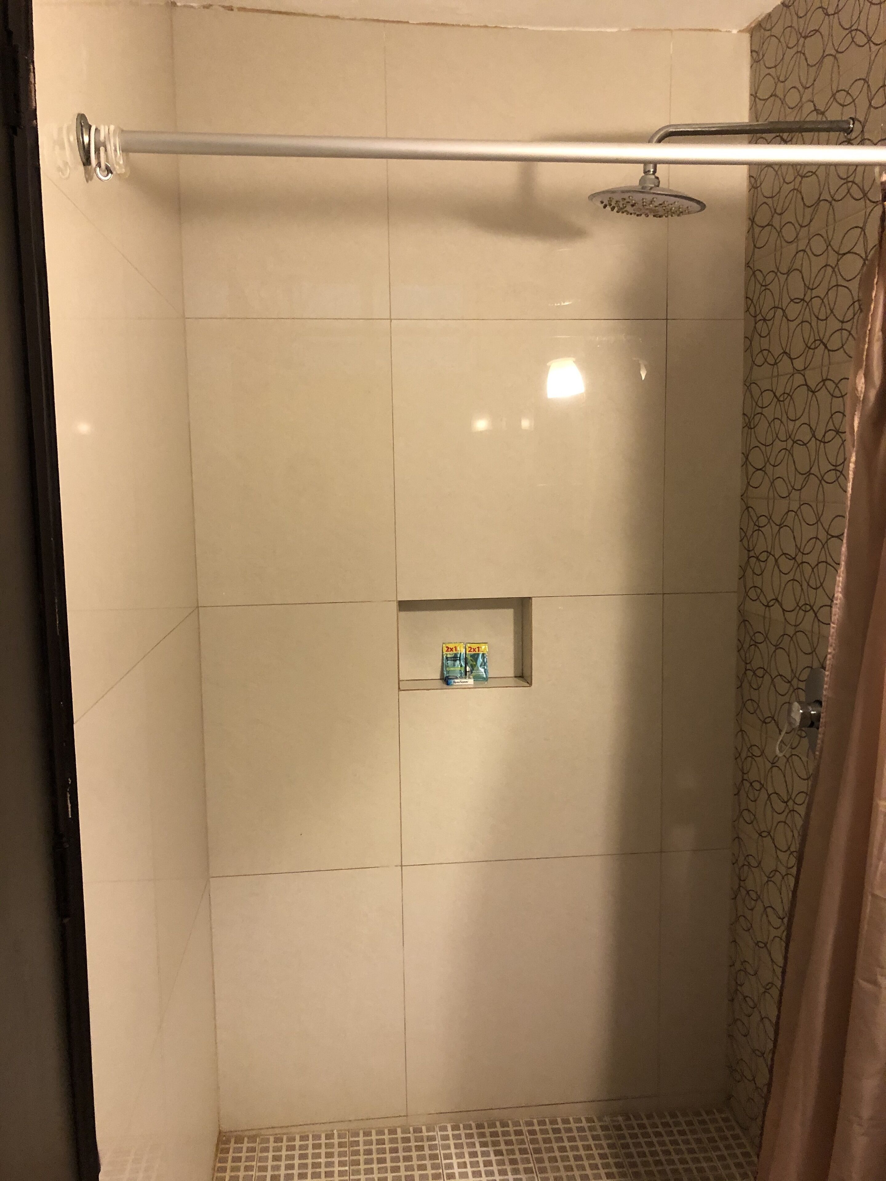 A shower area with a glass door, a showerhead, and a towel rack.