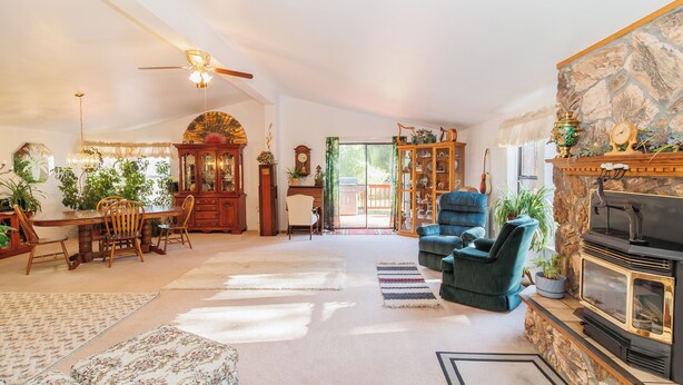 A spacious living room with a fireplace, a dining area with a wooden table and chairs, and a cozy seating area with a blue armchair.