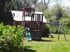 Explore a charming playhouse in our lush garden, complete with a slide and ladder for easy access.
