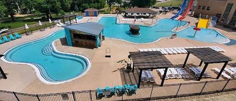 A swimming pool area with a water slide, lounge chairs, and a covered seating area.