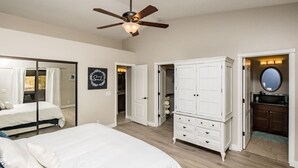 A bedroom with a bed, a wardrobe, a ceiling fan, and a bathroom with a mirror.