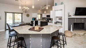 A spacious kitchen with a large island, bar stools, and pendant lighting.