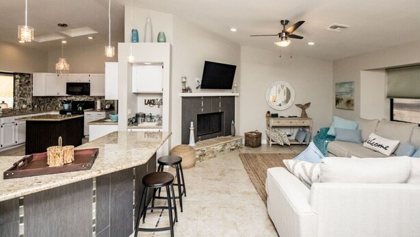 A modern kitchen with a central island, bar stools, and a fireplace.