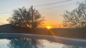 A swimming pool with inflatable rings and a sunset in the background.