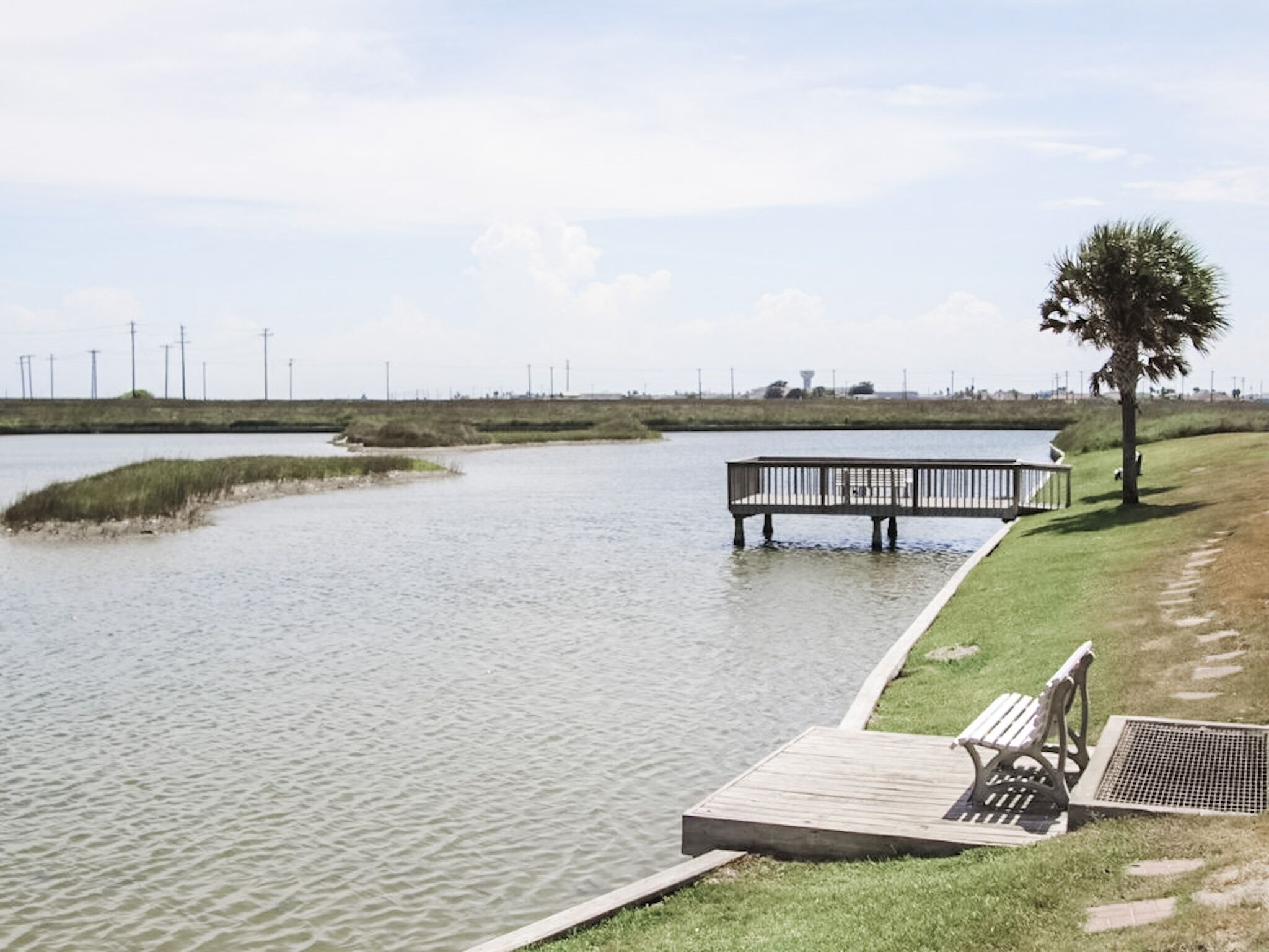 A riverside walkway with a wooden dock and benches.