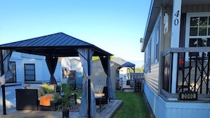 A residential area with a covered patio, outdoor seating, and a well-maintained lawn.