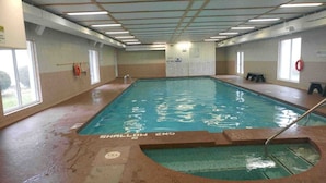 An indoor swimming pool with clear water, marked lanes, and a shallow end.