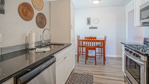 A kitchen with a dishwasher, a stove, and a dining area with a table and chairs. - Walk to UNM, 1bd/1ba, Clean! (Albuquerque)