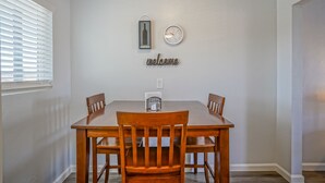 A dining area with a wooden table and chairs, a wall clock, a bottle-shaped decoration, and a 'welcome' sign. - Walk to UNM, 1bd/1ba, Clean! (Albuquerque)