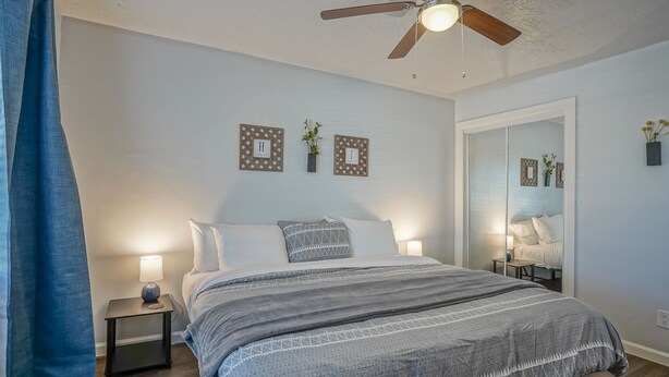 A bedroom with a bed, bedside tables, a ceiling fan, and wall decorations. - Walk to UNM, 1bd/1ba, Clean! (Albuquerque)