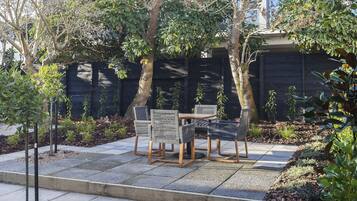 A patio area with a table and chairs, surrounded by trees and plants.