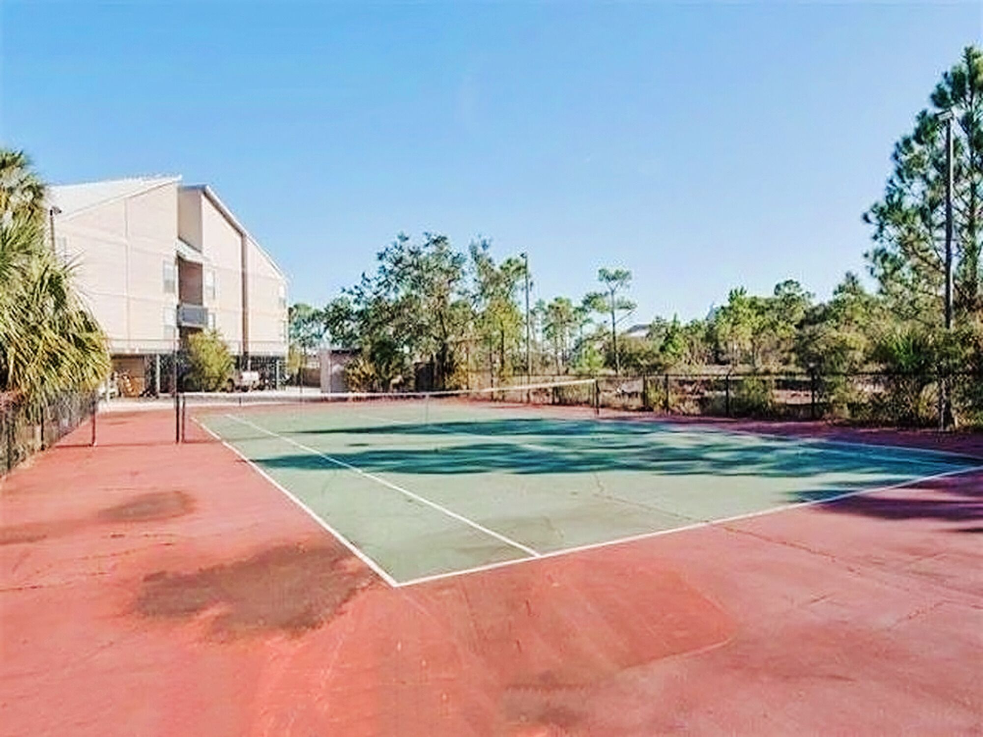 An outdoor tennis court with a building in the background.