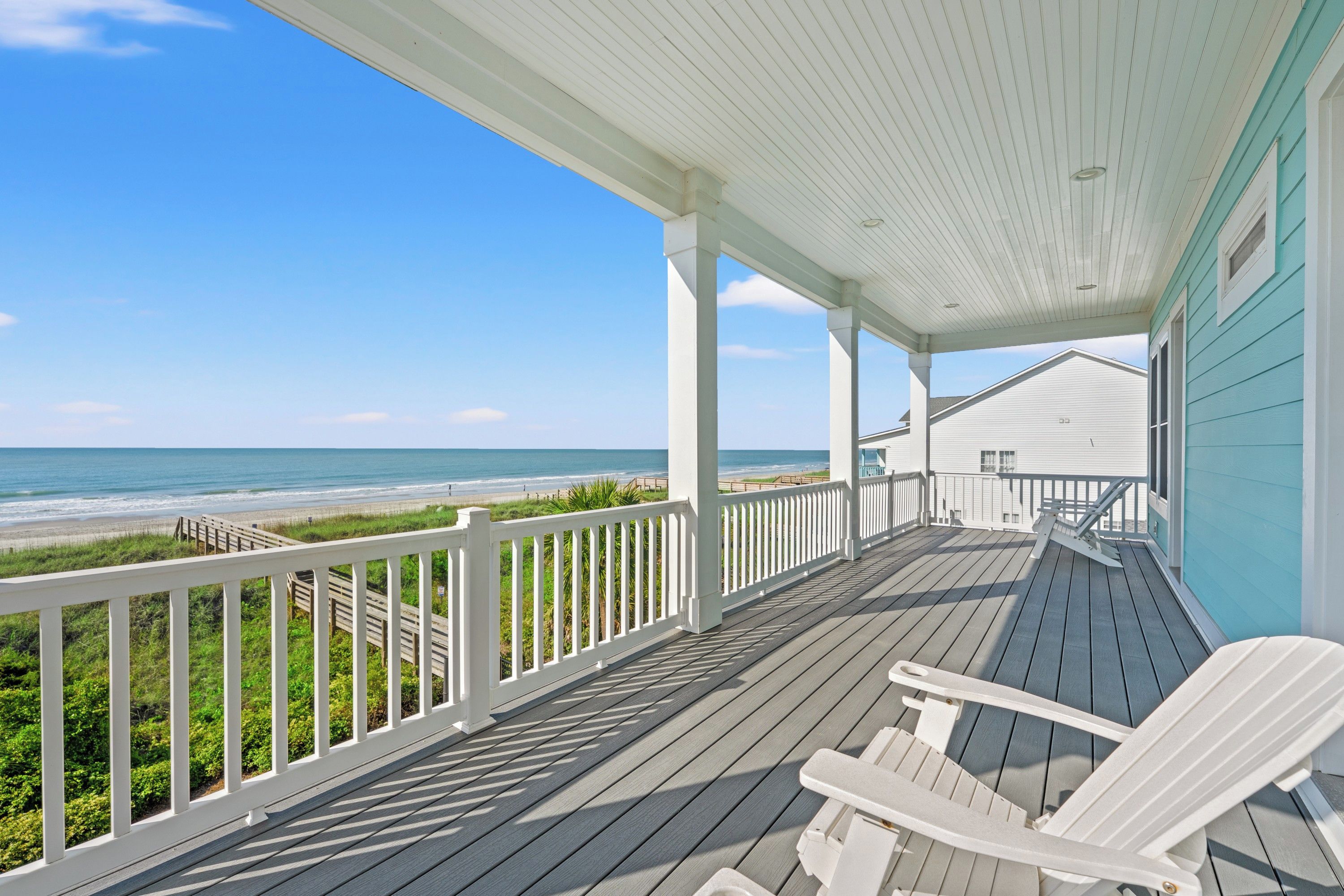 A covered porch with a view of the beach and ocean.
