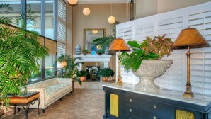 A spacious lobby with a large seating area, a fireplace, and multiple potted plants.