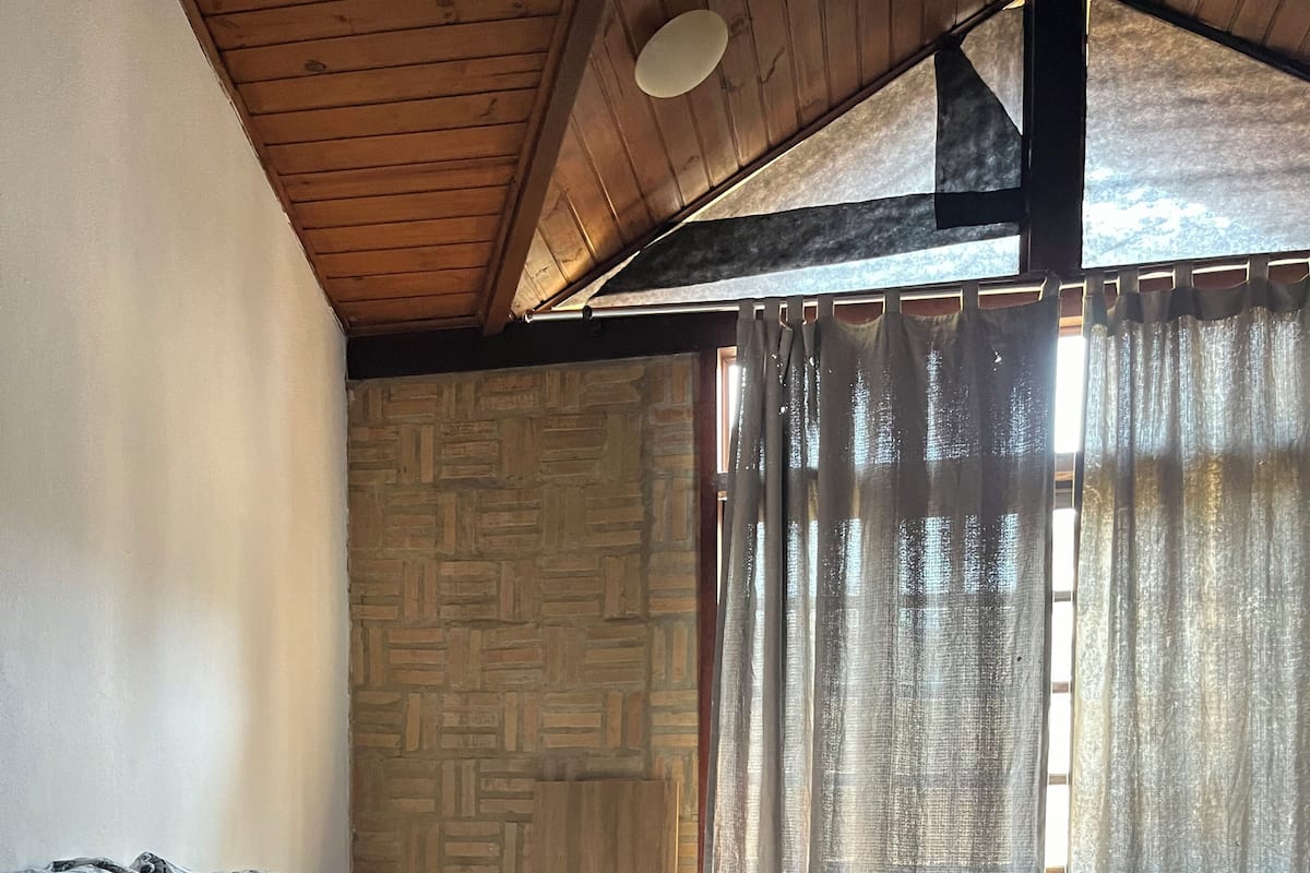 Un dormitorio con cama, colcha estampada y pared con diseño de piedra.