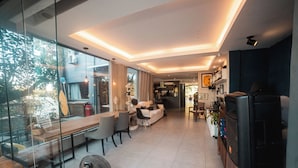 Una sala de estar moderna con pared de vidrio, comedor y cocina.