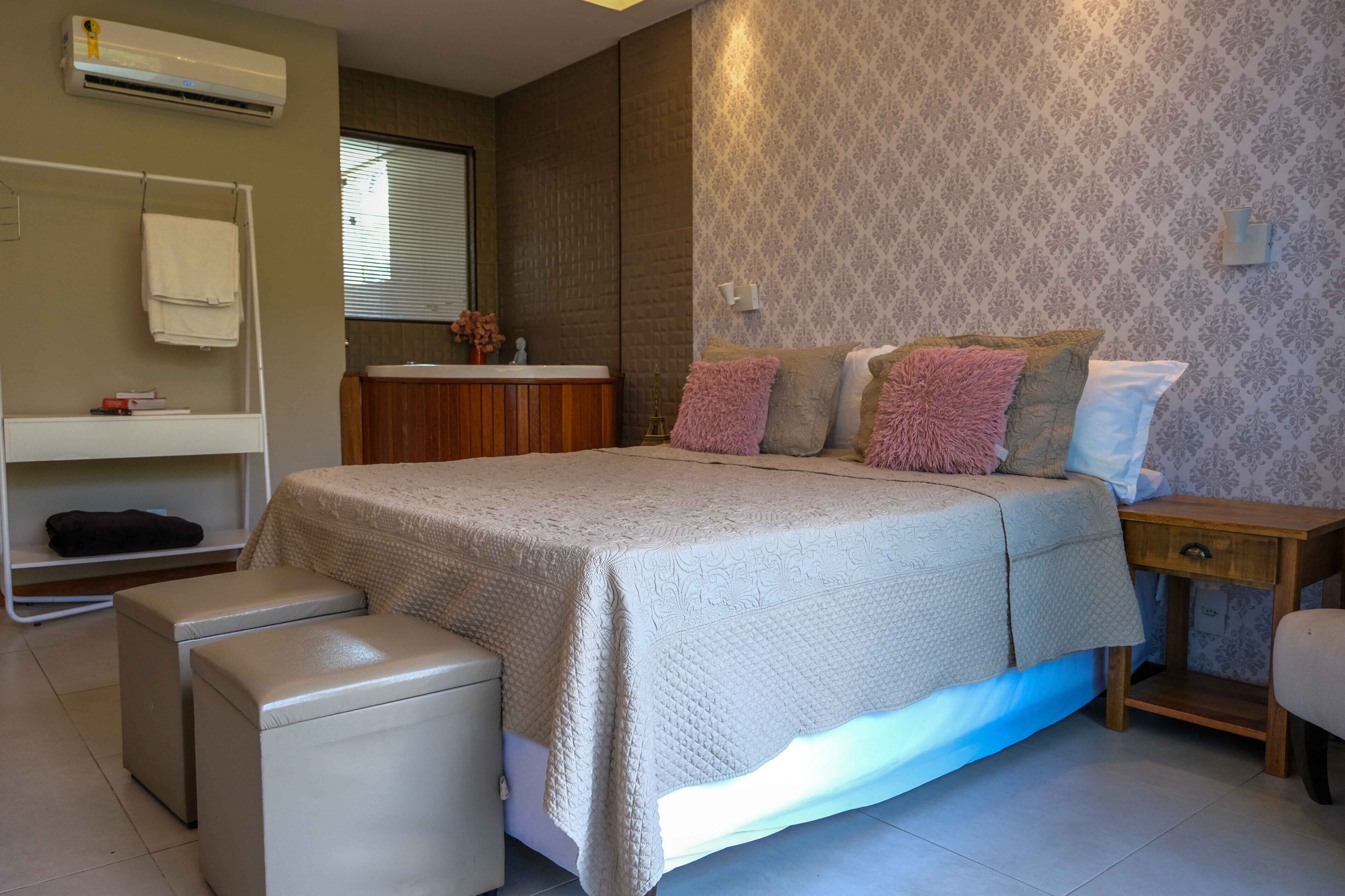 Une chambre à coucher comprenant un lit, des tables de chevet, une commode, une coiffeuse avec un miroir et un porte-serviettes.