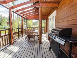 An outdoor wooden deck with a grill, a table, and chairs. - Villa valo by Interhome (Lieksa)