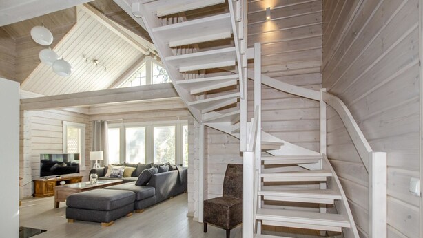 A spacious living area with a modern staircase, a comfortable sofa set, and a television.