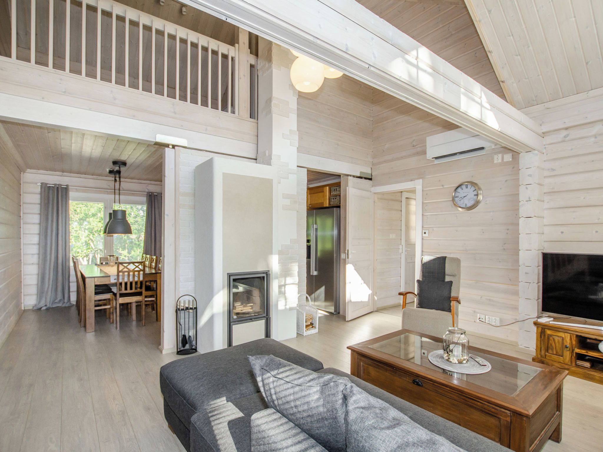 A spacious living area with a sofa, a glass coffee table, a fireplace, and a television.