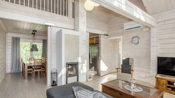 A spacious living area with a sofa, a glass coffee table, a fireplace, and a television.
