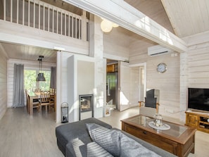 A spacious living area with a sofa, a glass coffee table, a fireplace, and a television. - Villa valo by Interhome (Lieksa)