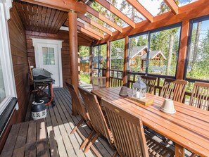 A wooden deck with a table and chairs, a grill, and a lantern. - Villa valo by Interhome (Lieksa)