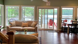 A cozy living room with a sofa, a glass coffee table, and a ceiling fan.