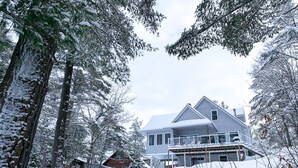 A two-story house with a covered porch and a snow-covered landscape.