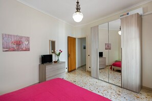 Une chambre à coucher comprenant un lit, une commode, un miroir et une porte donnant sur une autre pièce.