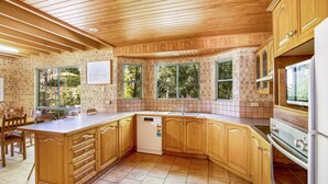 Una cocina con armarios de madera, lavavajillas y ventanas grandes.