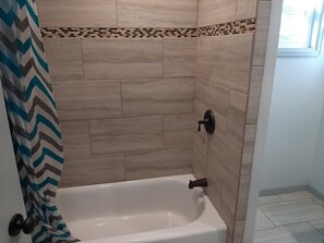 Bañera con ducha, toallas, jabón, shampoo