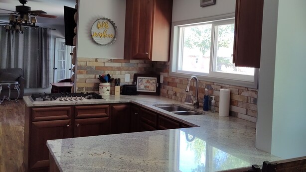 A modern kitchen with granite countertops, wooden cabinets, and a central island. - Get away from the hustle and bustle in an outdoor paradise! (Saratoga)
