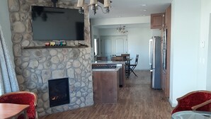 A spacious living area with a stone fireplace, wooden flooring, and a television mounted on the wall. - Get away from the hustle and bustle in an outdoor paradise! (Saratoga)