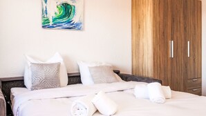 A hotel room with a bed, pillows, a wooden wardrobe, and a painting on the wall. - Arnica 16 by Interhome (Nendaz)