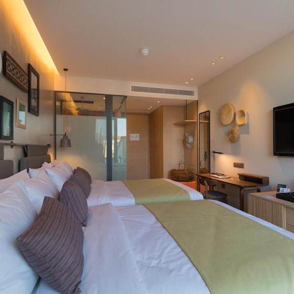 A hotel room with two beds, a desk, a chair, a TV, and a mirror. - Indigo Hotel - Adults Only (Larnaca)