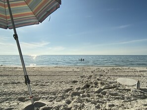 Relax on the beach with a shaded spot under the umbrella, perfect for a day of swimming and sunbathing.