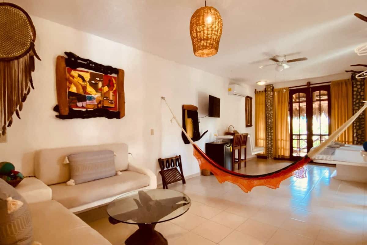 A spacious living area with a hammock, a sofa, a coffee table, and a dining table.