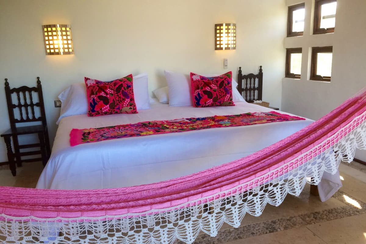 A bed with a pink and white canopy, two pillows, and a white bedspread.