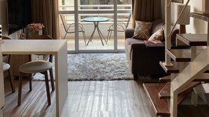 Un salon moderne comprenant un coin repas, un canapé, un téléviseur et un escalier.