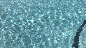 Una piscina con acqua cristallina, circondata da sdraio e un'area relax coperta.