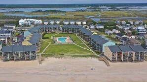 Una località balneare con piscina centrale, diversi edifici e spiaggia.