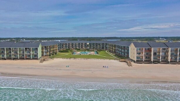 Un hotel sulla spiaggia con diversi edifici, una piscina e una spiaggia sabbiosa.