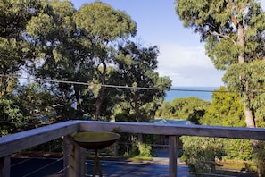 A balcony with a view of a coastal landscape, surrounded by trees.