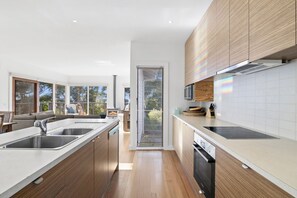 A modern kitchen with wooden cabinets, a central island, and a view to an outdoor seating area.