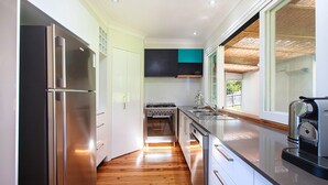 Een moderne keuken met roestvrijstalen apparatuur, witte keukenkastjes en uitzicht op het buitenlandschap door grote ramen.